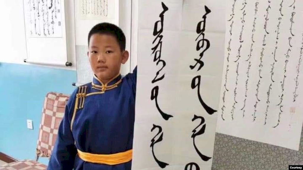 Un élève d'école primaire en Mongolie intérieure tient une bannière sur laquelle on peut lire 