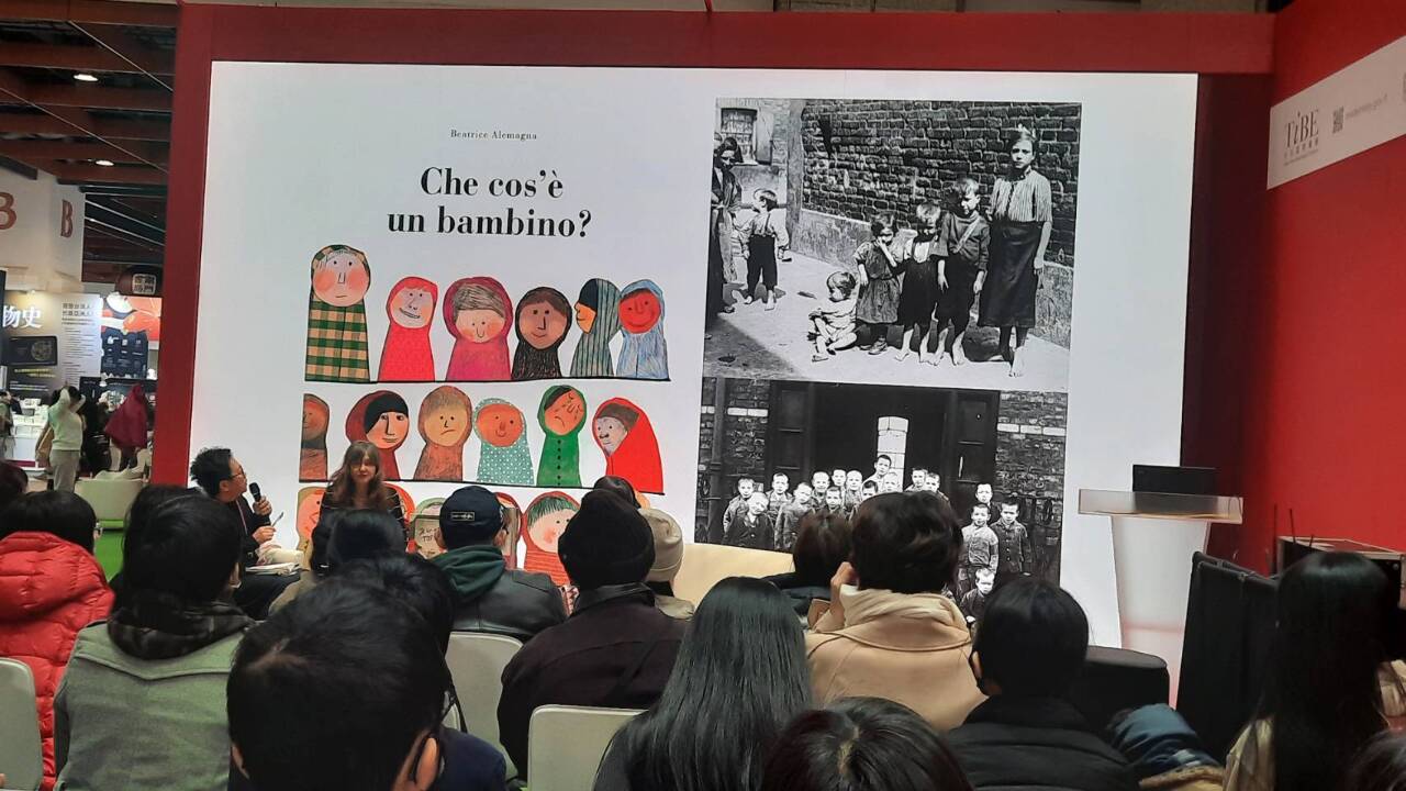 Conférence de Beatrice Alemagna au TIBE, où elle montre à gauche la couverture originale d'un de ses livres, et à droite les photos d'enfants ouvriers qui, pour un éditeur Anglais, y ressemblaient trop et faisaient qu'il fallait absolument la changer (photo Rti)